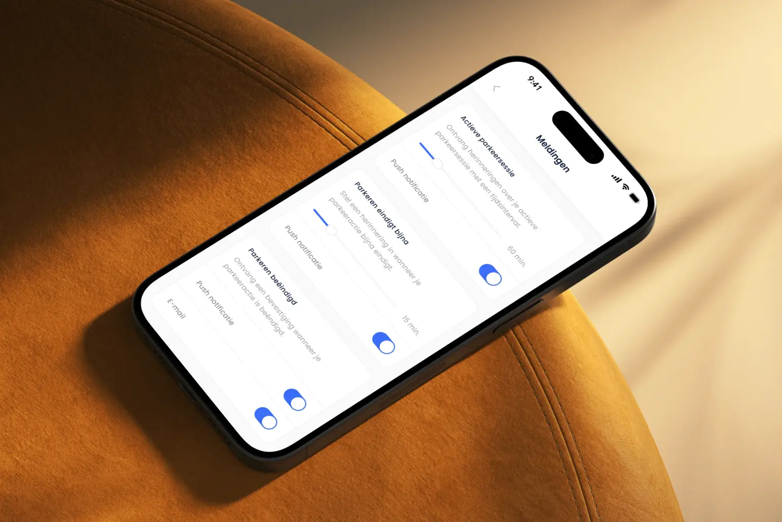 iPhone op een oranje stoel met het scherm Meldingen van de SimplePark-app, met per soort melding een schakelaar voor push en e-mail